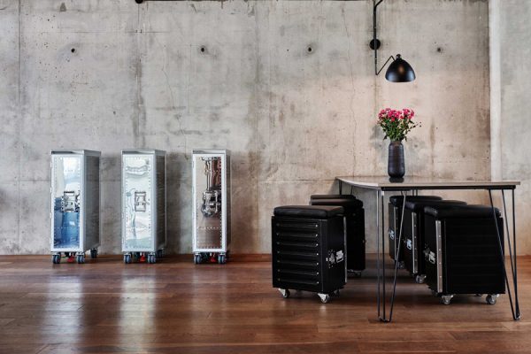 Three silver BordBar trolleys next to a set of suitcase-style chairs and a modern table.