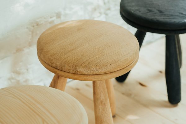 Set of three handcrafted stools in black, beech, and pine – clean-cut, overlapping composition.