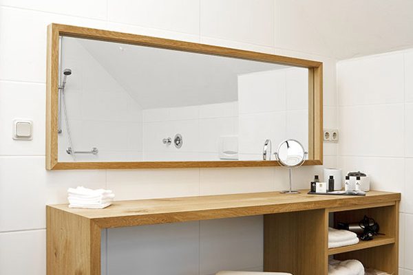 A single POMP stool in a bathroom, placed in front of a mirror and small cabinet.