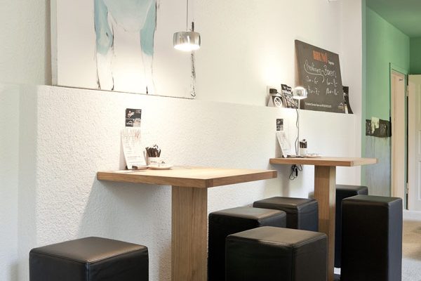 Several POMP bar stools at two high tables in a contemporary bar interior.