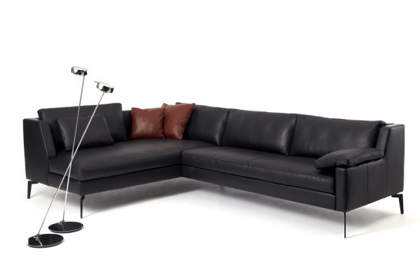 Black leather corner sofa from the Werther collection with high backrests and a floor lamp – modern and sophisticated setting.