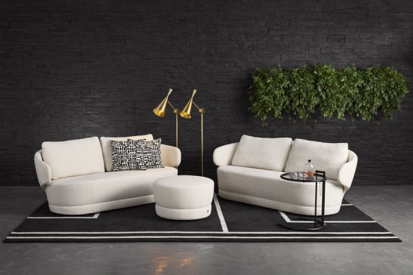 White upholstered sofas with soft curves and a matching round ottoman – contemporary living room setup