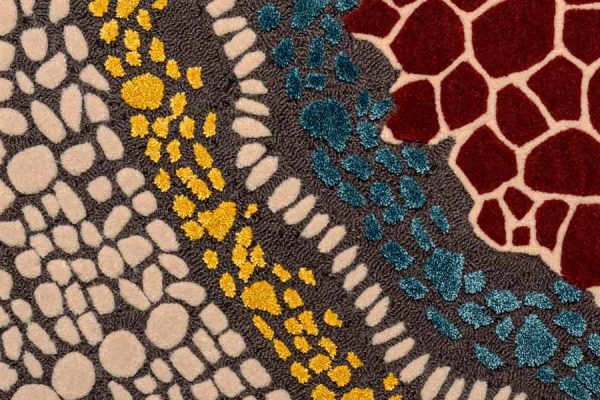 Detail view of the round rug showcasing vibrant textures and multi-colored dot patterns resembling abstract mosaic art.