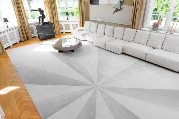 Spacious living room with white sectional sofa and oversized round rug in light grey sunburst design.
