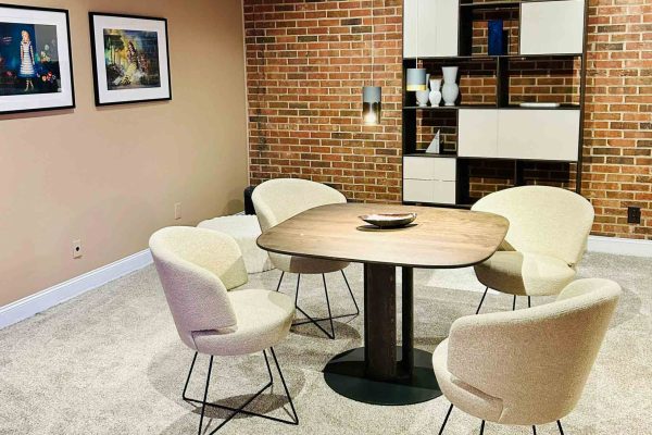 518 North showroom – dining setup with Werther upholstered chairs, a Rodam wooden pedestal table and wall art from Galerie Droste in front of an exposed brick feature wall