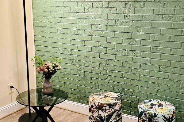 518 North showroom – Holtkötter floor lamp, Rodam glass side table, and two floral Pomp stools in front of a green brick wall