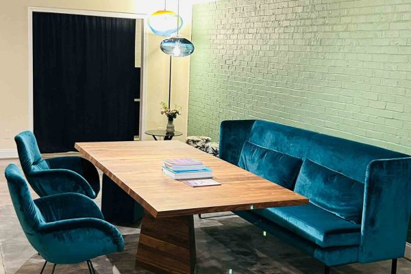 518 North showroom – Polstermöbel Werther seating group with teal velvet chairs and bench, Rodam wooden dining table, Pomp velvet stool, Eloah pendant lights, and a Boardbar trolley in the background